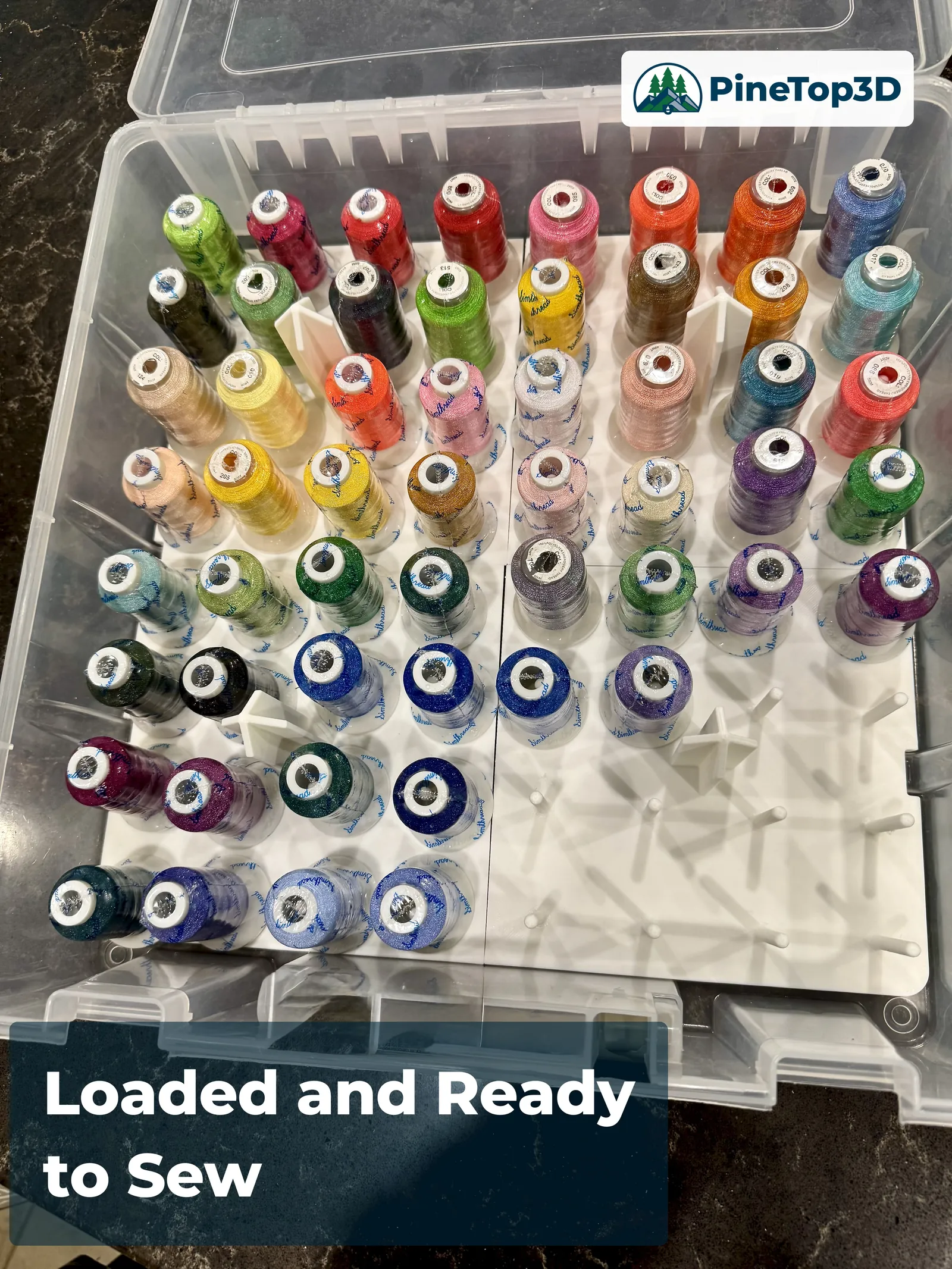 The printed holder loaded with large embroidery spools in the Artbin box, lift handles and pins visible